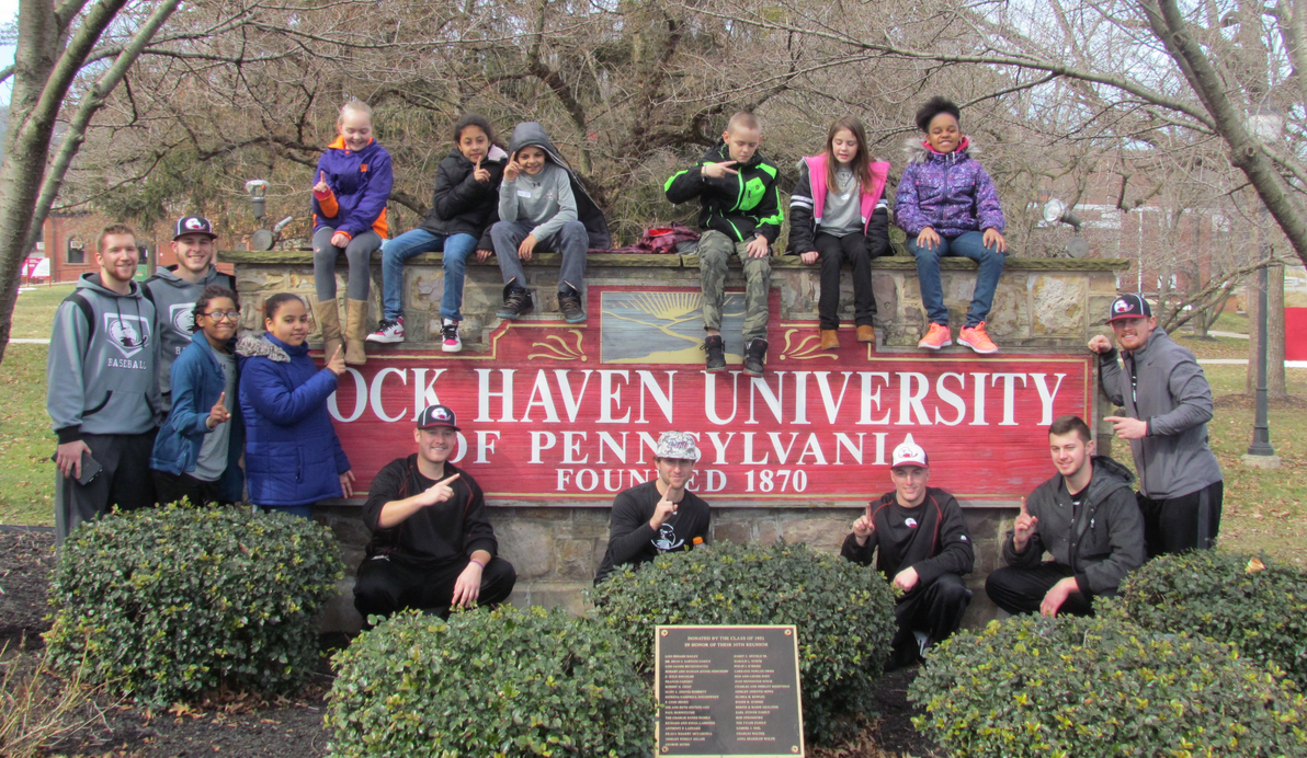 kids and mentors around lock haven university sign