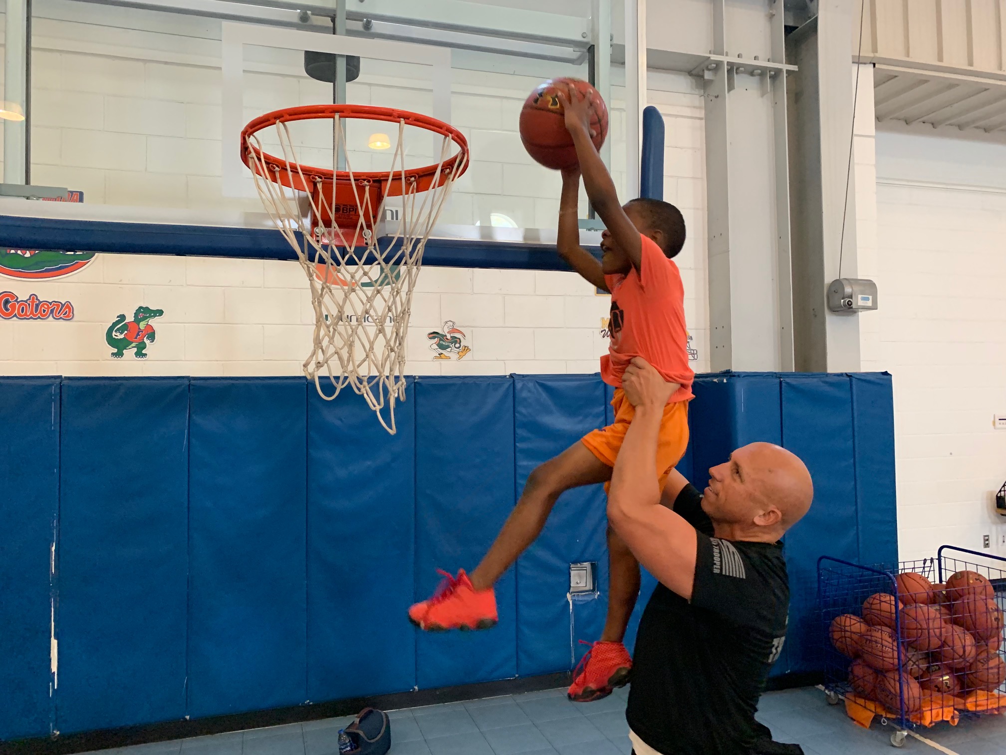 Lt. Greg Bueno helping a member of the Boys & Girls Clubs of Collier County dunk a basketball